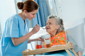 Nurse assisting a senior during her meals