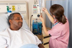 Nurse checking some medical equipment while the senior is sleping in bed